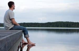 man with opioid addiction sits near the water