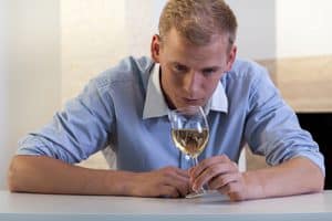 man looking at glass of wine wonders, "is alcohol a drug"