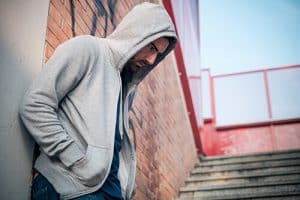 man wearing a hoodie in a stairwell has a crystal meth problem