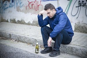 man drinking on sidewalk has alcohol dependence