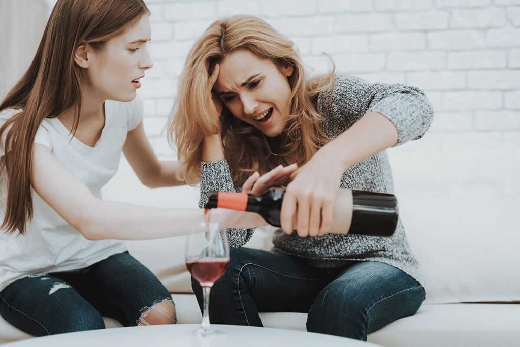 two women argue over a bottle of wine drunk due to alcohol and anxiety