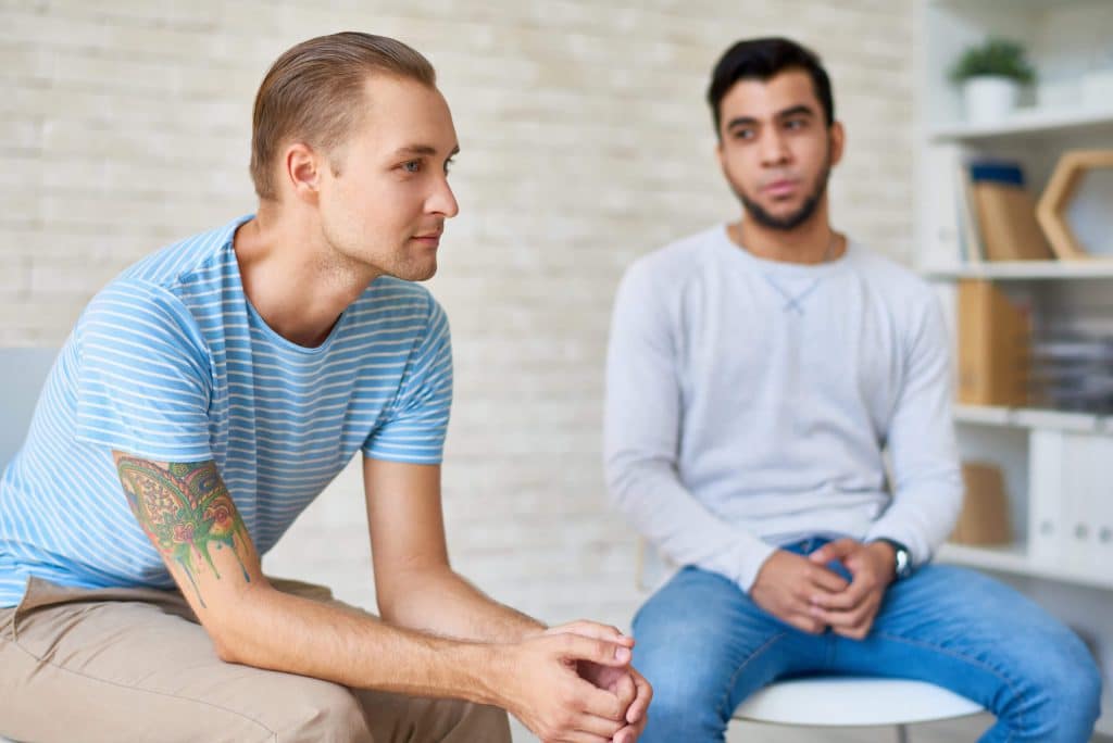 Support group sitting in circle and sharing their problems with other members during productive therapy session at cozy psychologists office