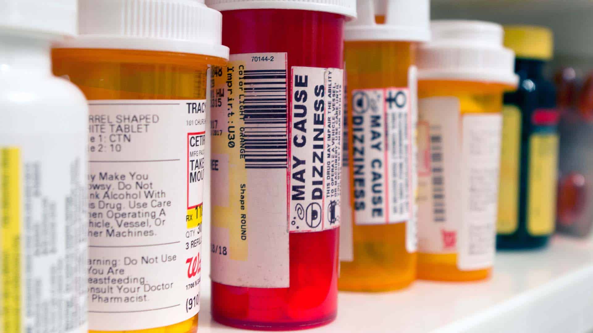 pill bottles lined on a shelf with a warning that may cause dizziness
