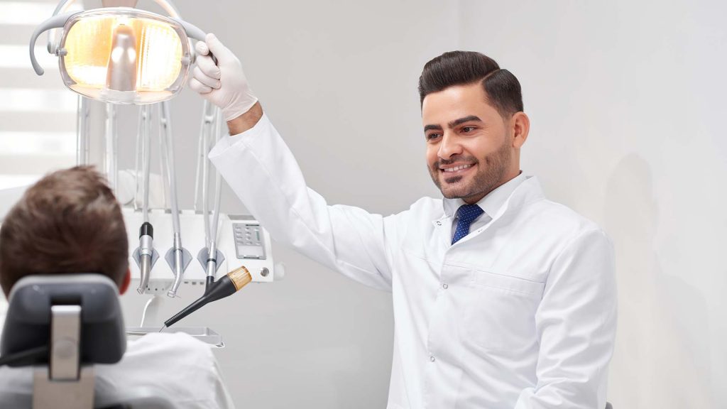 Shot of a male dentist adjusting lamp before dental examination of the teeth of his patient copyspace professionalism friendly experienced medicine healthcare dentistry.