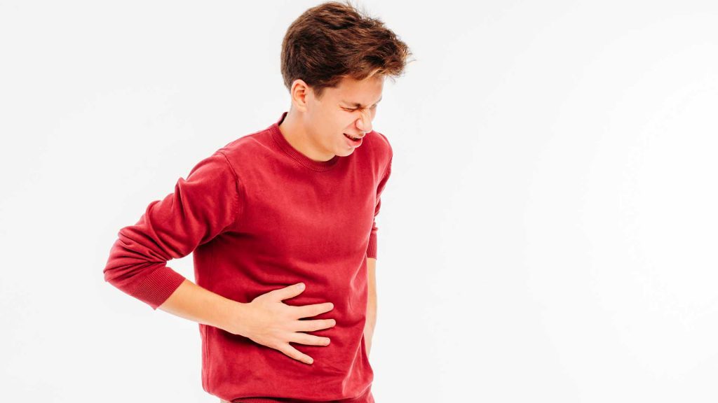 Young man holding liver, experiencing pain, on white background