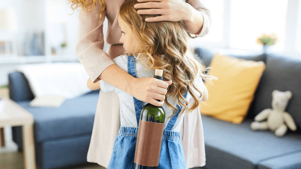 mother hugging her daughter holding a bottle of alcohol